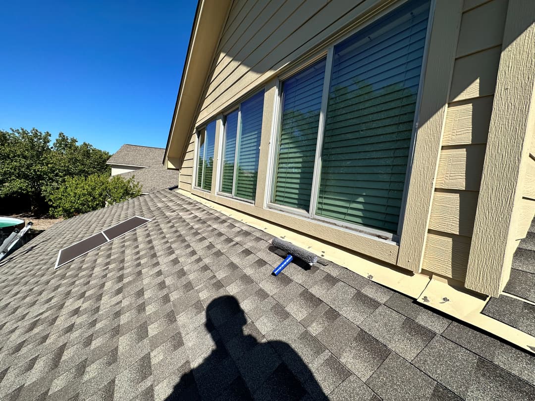 Roof with solar panel installation, featuring a roller brush and sunny blue sky.